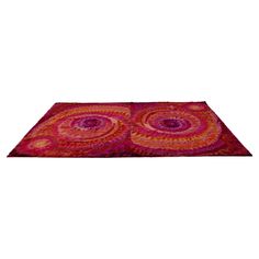 a red and pink area rug with circular designs on the center, in front of a white background