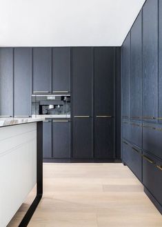 an empty kitchen with black cabinets and white counter tops