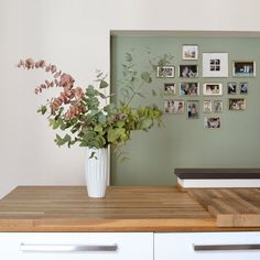 a vase filled with flowers sitting on top of a wooden table next to a wall