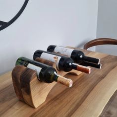 three bottles of wine are placed in a wooden holder on top of a wood table