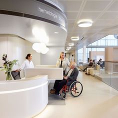 two women and a man in a wheelchair at the front desk of a medical office