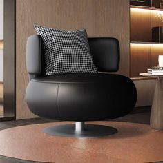 a black chair sitting on top of a wooden floor next to a table and lamp