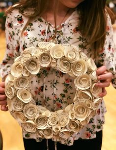 a woman holding a wreath made out of rolled up paper