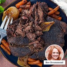 a blue plate topped with meat and carrots next to a fork on top of a wooden table