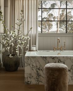 a marble bathtub in front of a large window