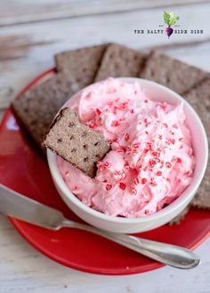 a bowl filled with ice cream and crackers on top of a red plate