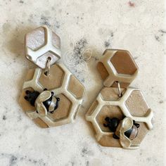 two pairs of earrings sitting on top of a marble countertop next to each other