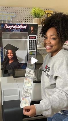 a woman holding up a fake graduation cap and money in front of a computer screen