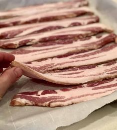 bacon is being prepared on a sheet of wax paper for making pizzas or appetizers