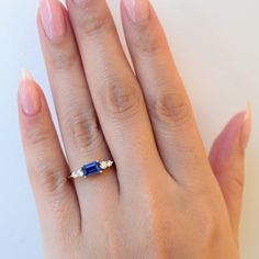 The high contrast combination of vivid blue sapphires and twinkling white diamonds has stood the test of time and Anna Sheffield makes it her own with this compact ring that's easy to wear, yet loaded with personality. The east-west setting is a perfect way to turn a sizable sapphire into an everyday statement. Understated brides and gemstone lovers will both find something to love about this ring. Designed in New York. 14 karat gold set with an approximately 0.75 carat (6 mm x 4 mm) emerald-cut Timeless Radiant Cut Sapphire Ring, Timeless Emerald-cut Sapphire Ring, Timeless Blue Radiant Cut Sapphire Ring, Three Stone Sapphire Ring With Radiant Cut Diamond, Fine Jewelry Tanzanite Three Stone Sapphire Ring, Sapphire Diamond Ring With Baguette Cut And Accent Stones, Timeless Baguette-cut Sapphire Ring, Timeless Blue Sapphire Three-stone Ring, Timeless Blue Sapphire Three Stone Ring