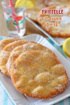 three lemon cookies on a white plate next to a glass of water and two glasses