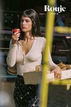 a woman is holding an apple and looking at the camera