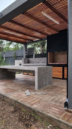 an outdoor bbq with grills and benches under a pergolated roof on a deck