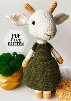 a crocheted sheep in a green dress next to a plant and yarn ball