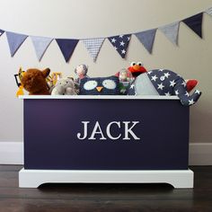 a toy chest with stuffed animals in it and bunting on the wall behind it