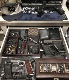 an assortment of men's watches and other items in a drawer on display at a store