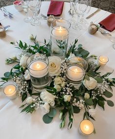 an arrangement of flowers and candles on a table