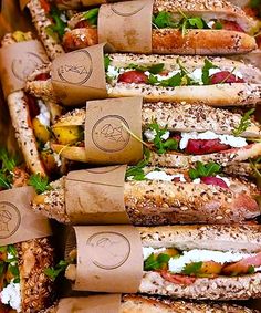 a bunch of sandwiches are stacked on top of each other in brown paper wrappers