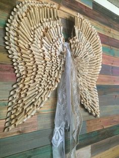 an angel made out of wood sticks on a wall next to a white lace ribbon