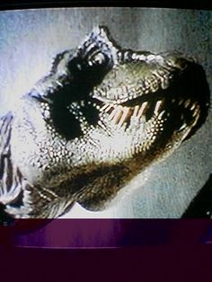 a close up of a television screen with a dinosaur on it's face and mouth