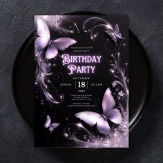 a birthday party card with purple butterflies and swirls on the front, sitting on a black plate