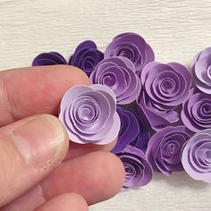 a hand holding a bunch of purple paper flowers