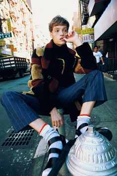 a young man sitting on top of a fire hydrant wearing striped socks and knee high socks