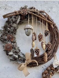 a wreath with pine cones and ornaments hanging from it's side on a wall