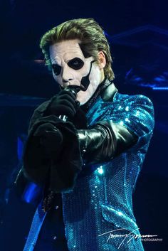 a man wearing a mask and holding a microphone in front of his face on stage