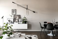 a dining room table with black chairs and pictures on the wall above it, next to a white couch