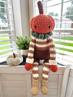 a knitted stuffed animal sitting on top of a window sill