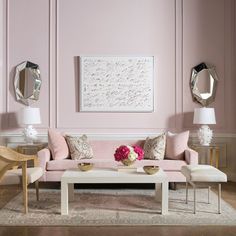 a living room with pink walls and furniture in the corner, along with mirrors on the wall