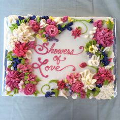 a white cake with flowers and the words showers of love written in pink on it