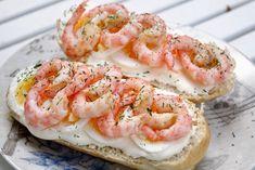 two pieces of bread topped with shrimp on top of each other and garnished with herbs