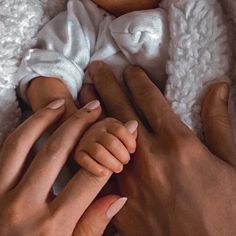 two hands holding a baby wrapped in a blanket