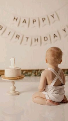 a baby sitting on the floor in front of a cake