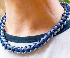 a close up of a person wearing a blue and white braided necklace on their neck