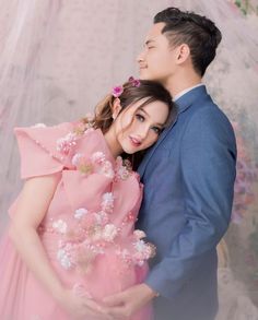 a man and woman are hugging each other in front of a white background with pink flowers