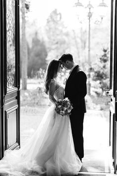 a bride and groom kissing in front of an open door