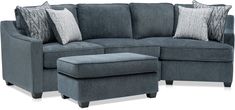 a blue sectional couch and ottoman with pillows