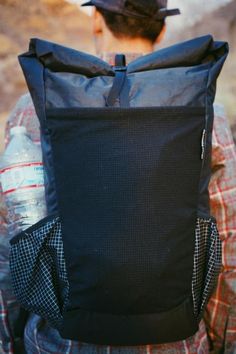 a person with a back pack and water bottle in their hand, looking down at the ground