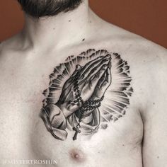 a man with a cross and praying hands tattoo on his chest