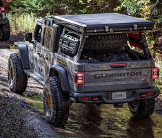 two jeeps driving down a muddy road in the woods