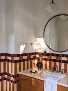 a bathroom sink sitting under a mirror next to a wooden cabinet with flowers in it