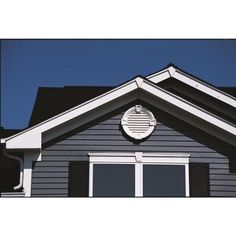 the top of a gray house with a clock on it's face and black shutters