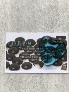 a blue heart shaped brooch sitting on top of a white piece of paper with words written below it