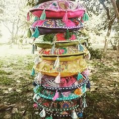 a stack of colorful bags sitting on top of a grass covered field next to a tree