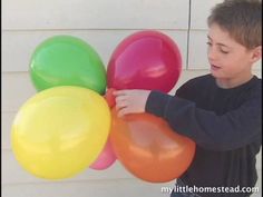 a young boy holding several balloons in his hands