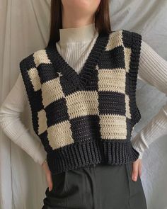 a woman wearing a black and white crocheted vest