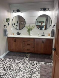 a bathroom with double sinks and two mirrors on the wall next to a rug that has been placed in front of it